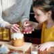A mother and daughter bonding while decorating an Easter cake together indoors.